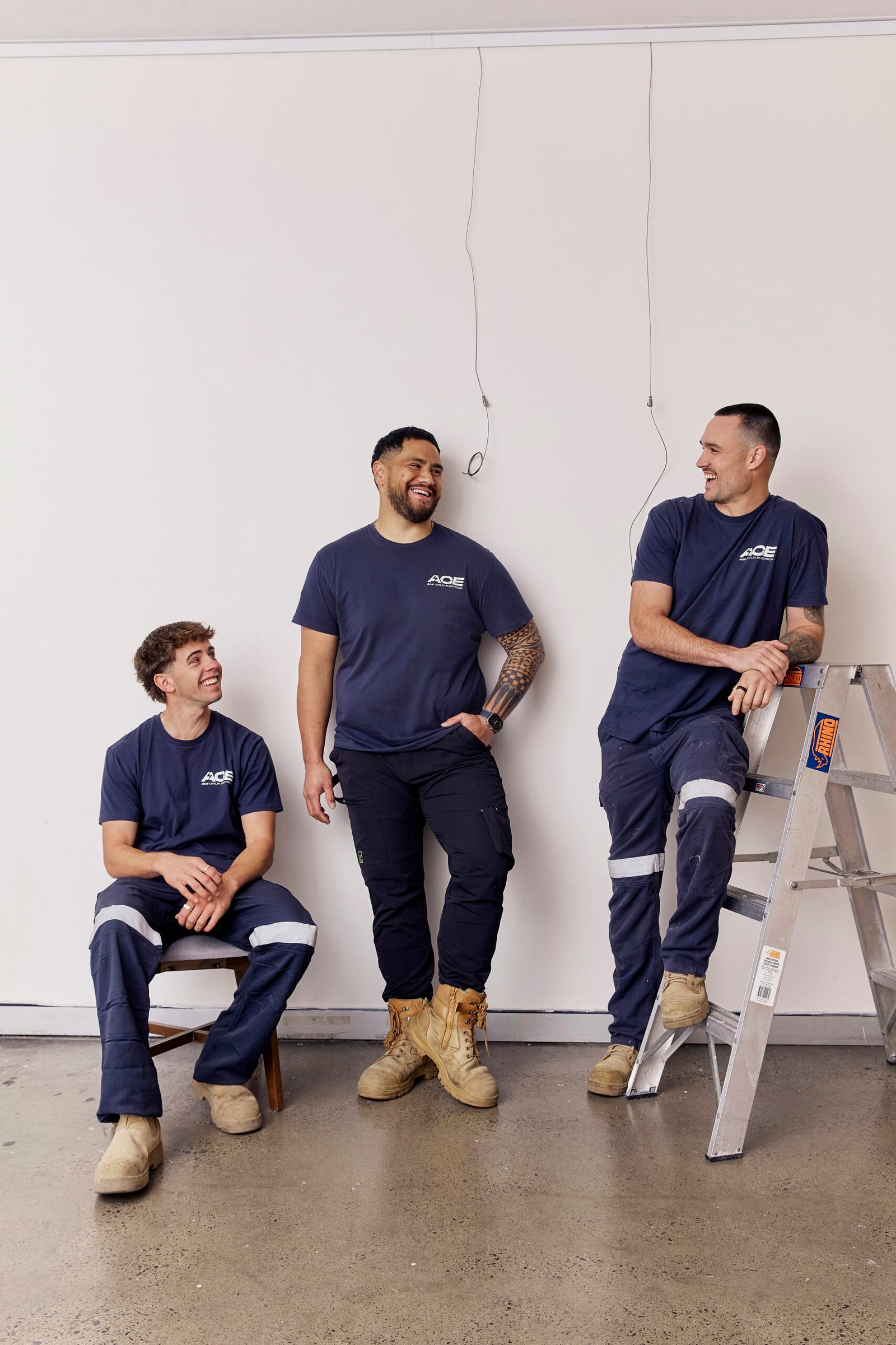 Three Ace Catlin Electrical team members in matching work uniforms posing together on a job site