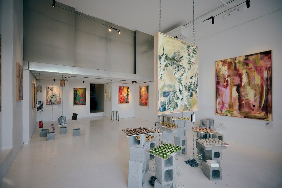 Spacious art display area with suspended artwork, exhibit stands, and directional track lights