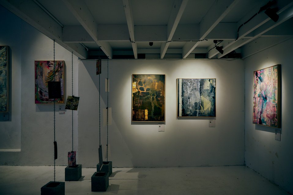 Art gallery interior with track spotlights focused on framed paintings mounted on white walls