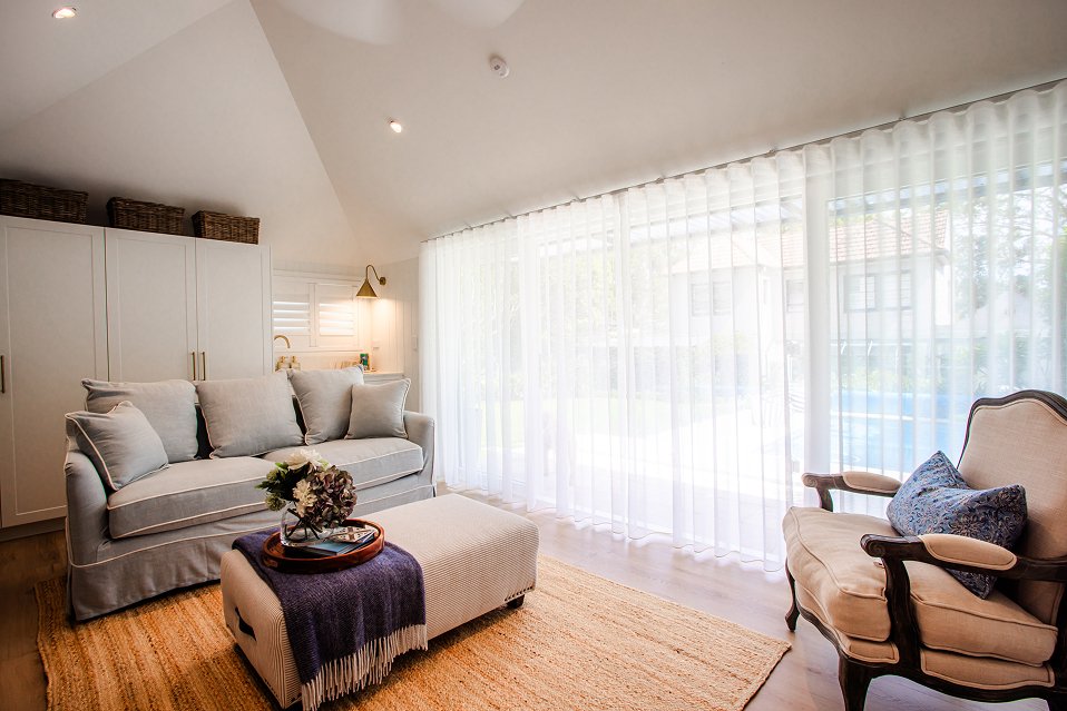 Bright living space with sheer curtains, armchair, and subtle ceiling LED downlights