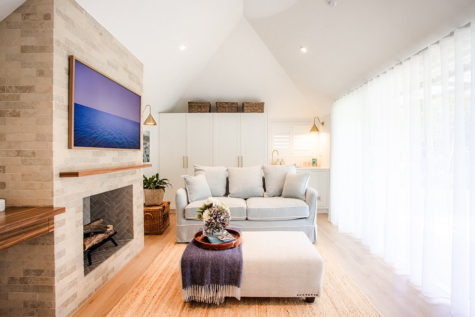 Living room featuring a wall-mounted TV, desk area with brass sconce, and recessed ceiling lights