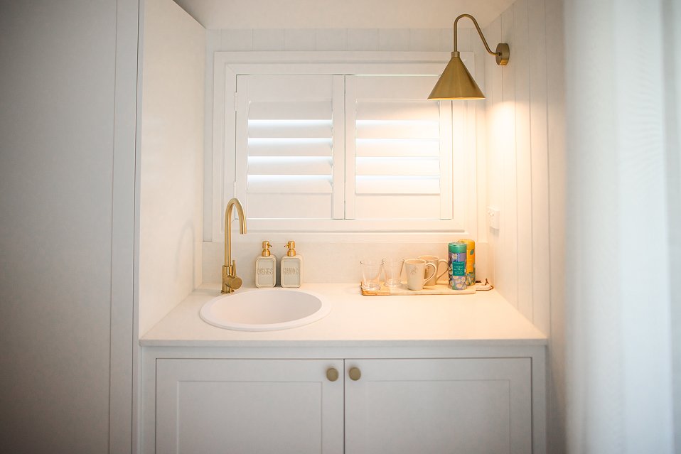 Elegant vanity nook with brass fixtures, vessel sink, and wall-mounted brass sconce light fixture