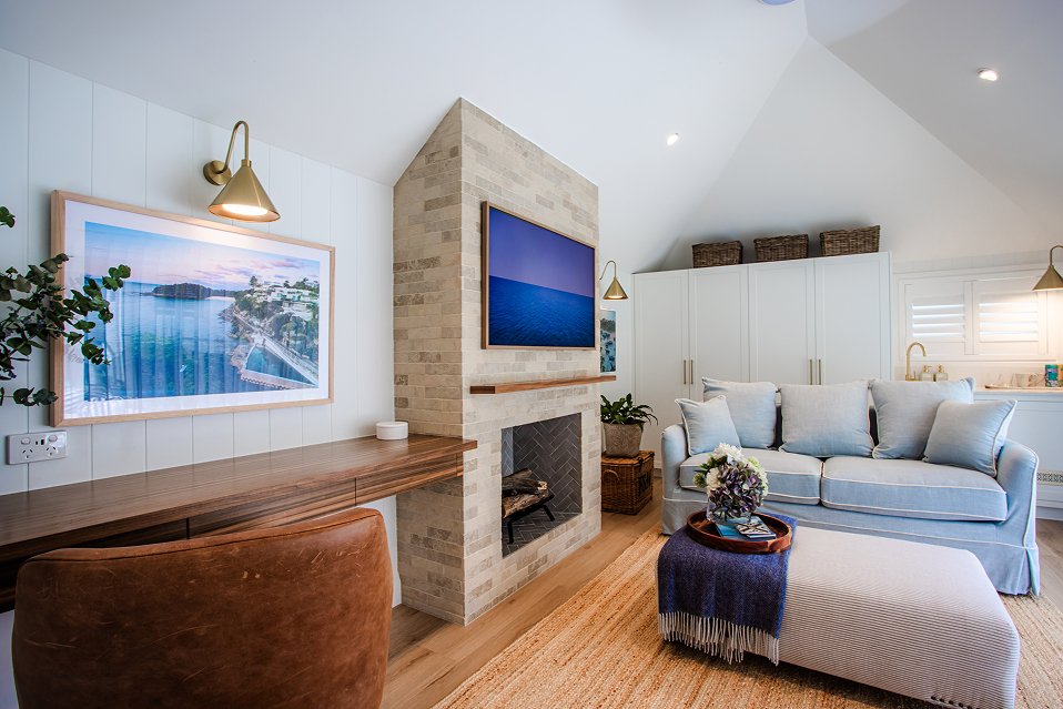 Living room featuring a wall-mounted TV, desk area with brass sconce, and recessed ceiling lights